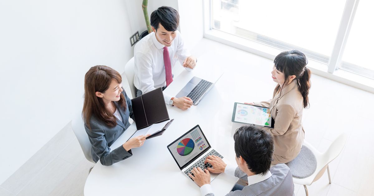パソコンやタブレットを囲んで会議をする男女