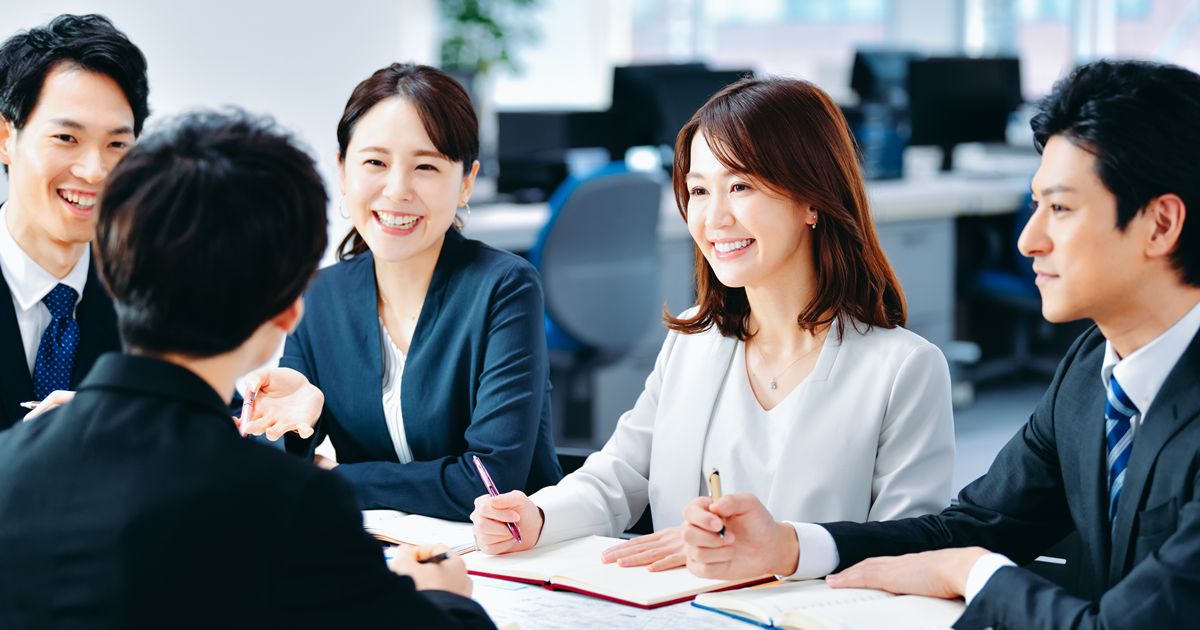 オフィスで笑顔で談笑する4人のビジネスパーソン