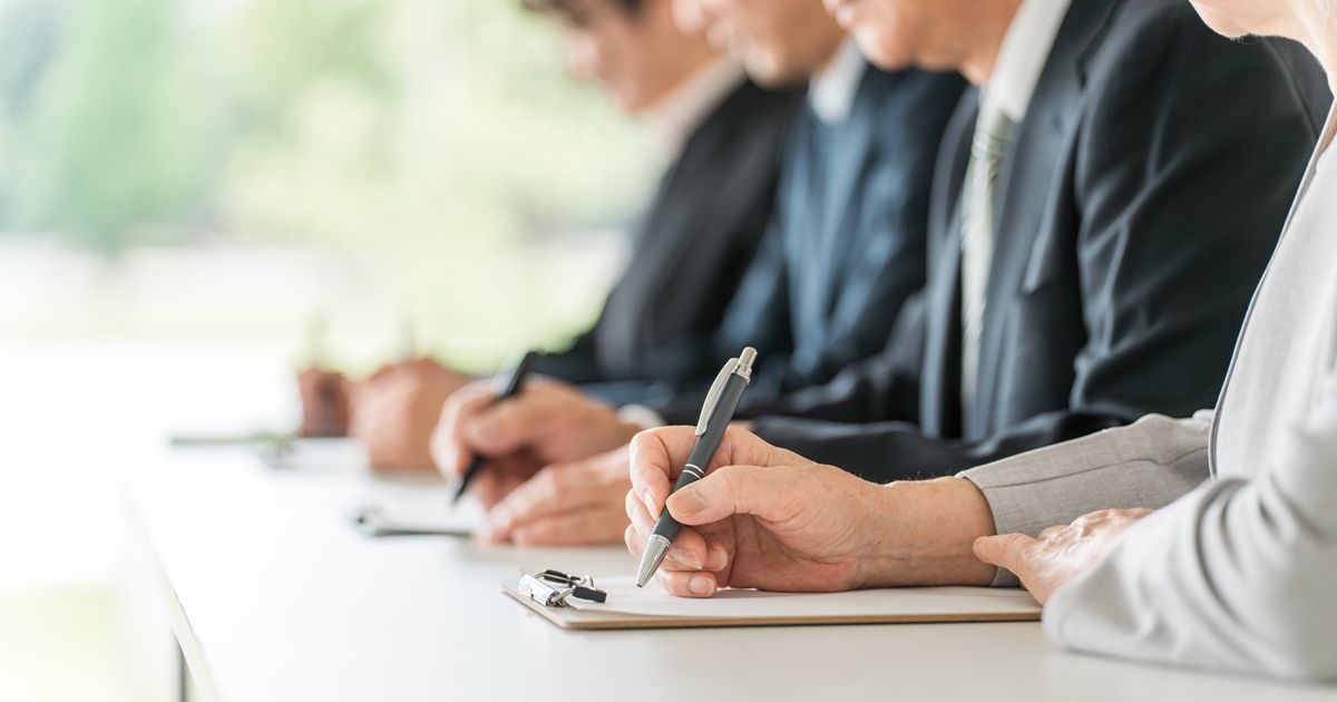 講習会でバインダーの資料にペンでメモを取る手元