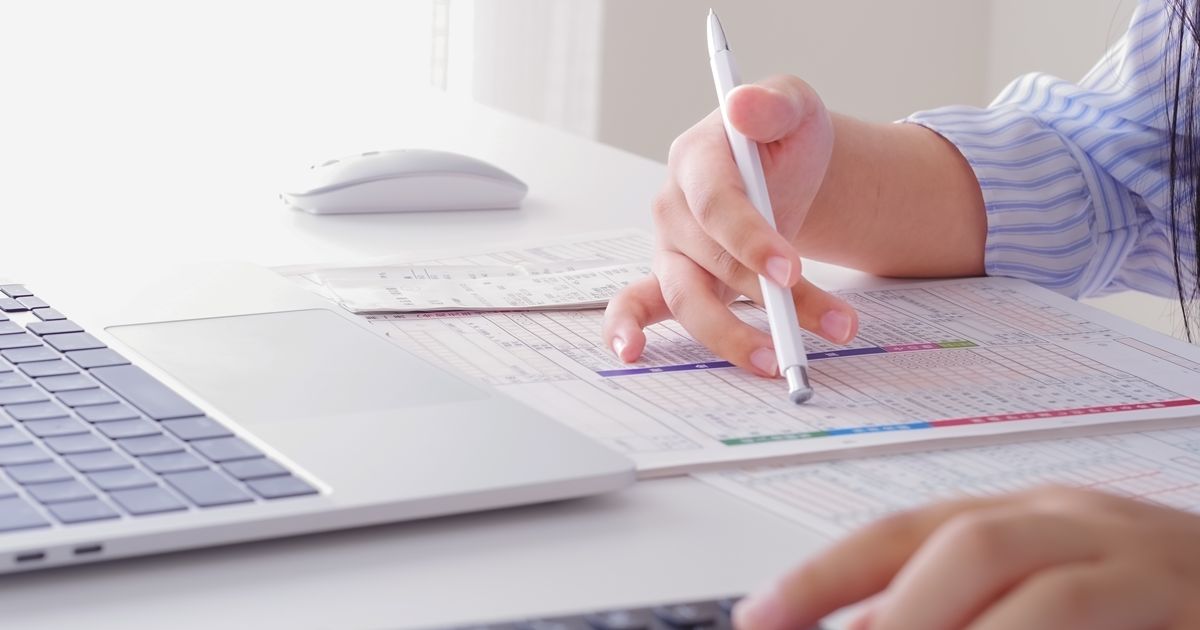 帳票を前にペンと電卓で計算作業をする手元