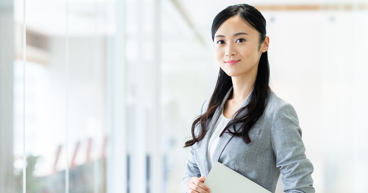 オフィスでファイルを抱え微笑む女性ビジネスパーソン