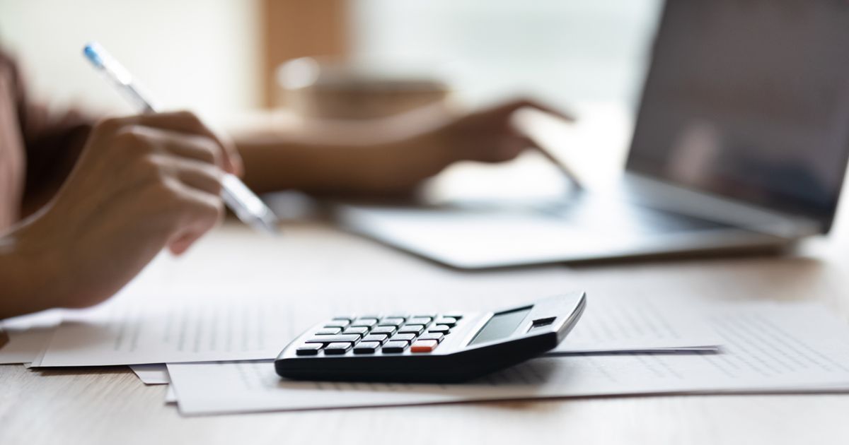 電卓とパソコンを使って書類の計算作業をする様子