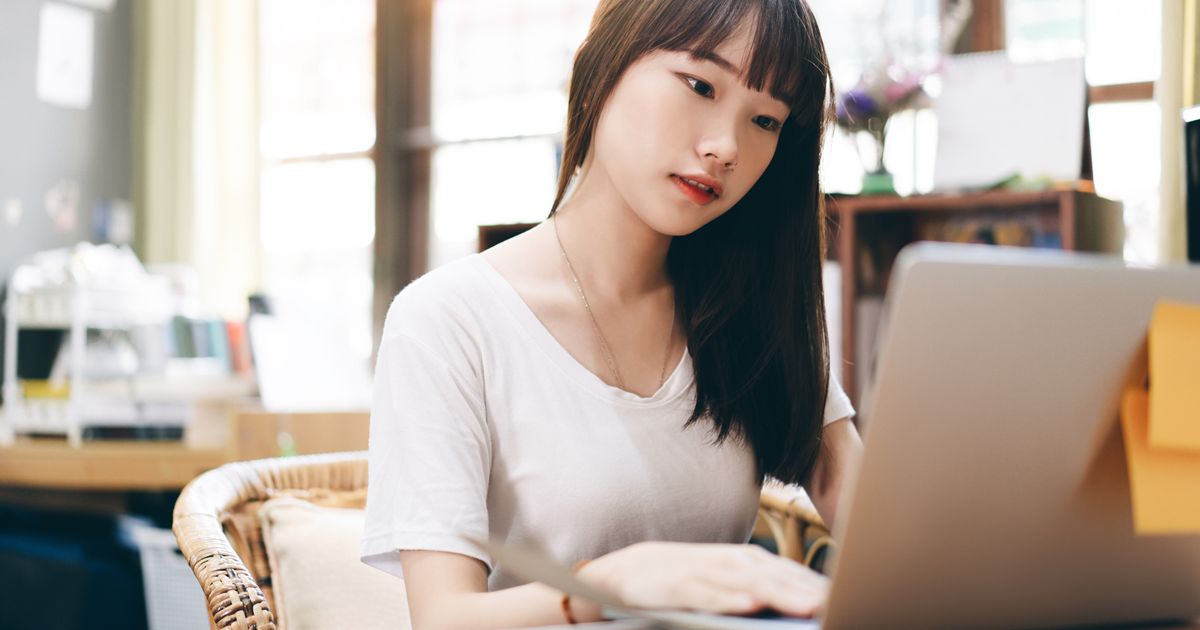 ノートパソコンの画面を真剣に見つめる若い女性