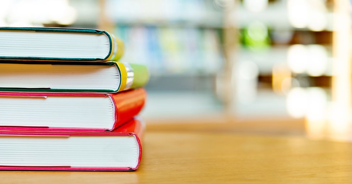 オフィスでノートパソコンやタブレットを持って並ぶ4人の男女