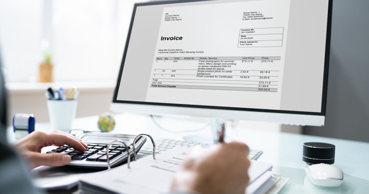 パソコン画面の請求書を見ながら計算機で集計する様子