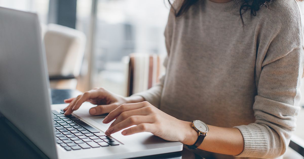 カフェでノートパソコンをタイピングする女性の手元