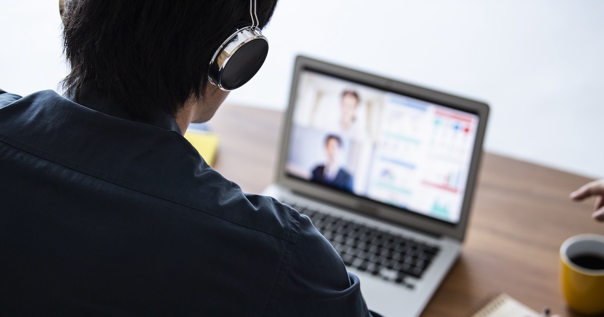 ヘッドホンをつけてパソコン画面を見る男性の背中