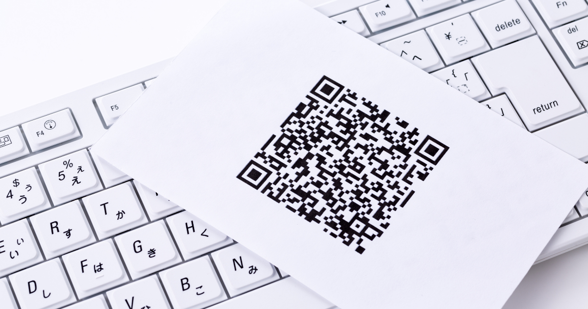 白いキーボードの上に、QRコードが印刷された紙が置かれている