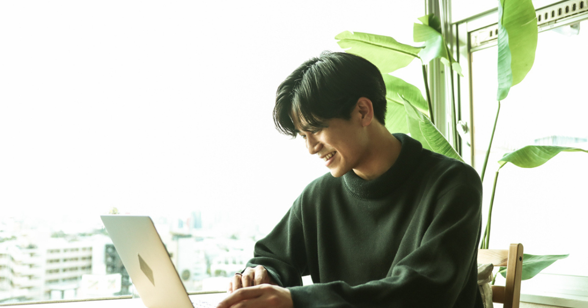 窓際でノートパソコンを操作する男性