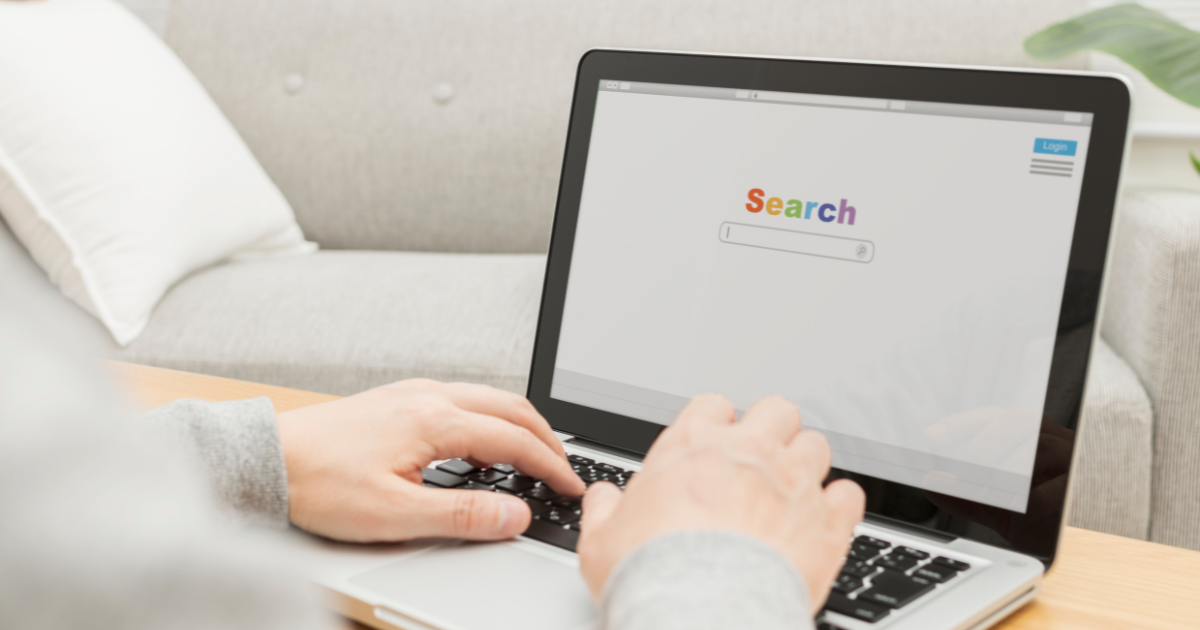 画面に検索ページが表示されているノートパソコンを操作している手元