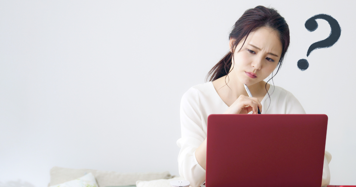 ノートパソコンを前に、疑問符を浮かべた表情で考え込む女性の様子