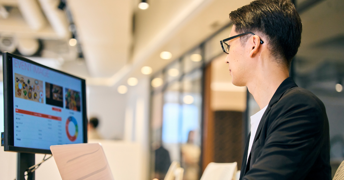 オフィスでスーツの男性がモニター画面を見ている様子