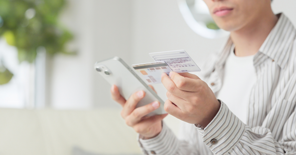 スマホとマイナンバーカードを両手に持つ人物