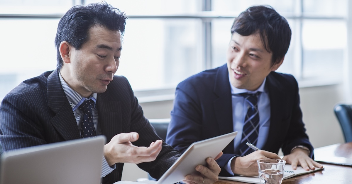 タブレットを使いながら上司と話すビジネスパーソン