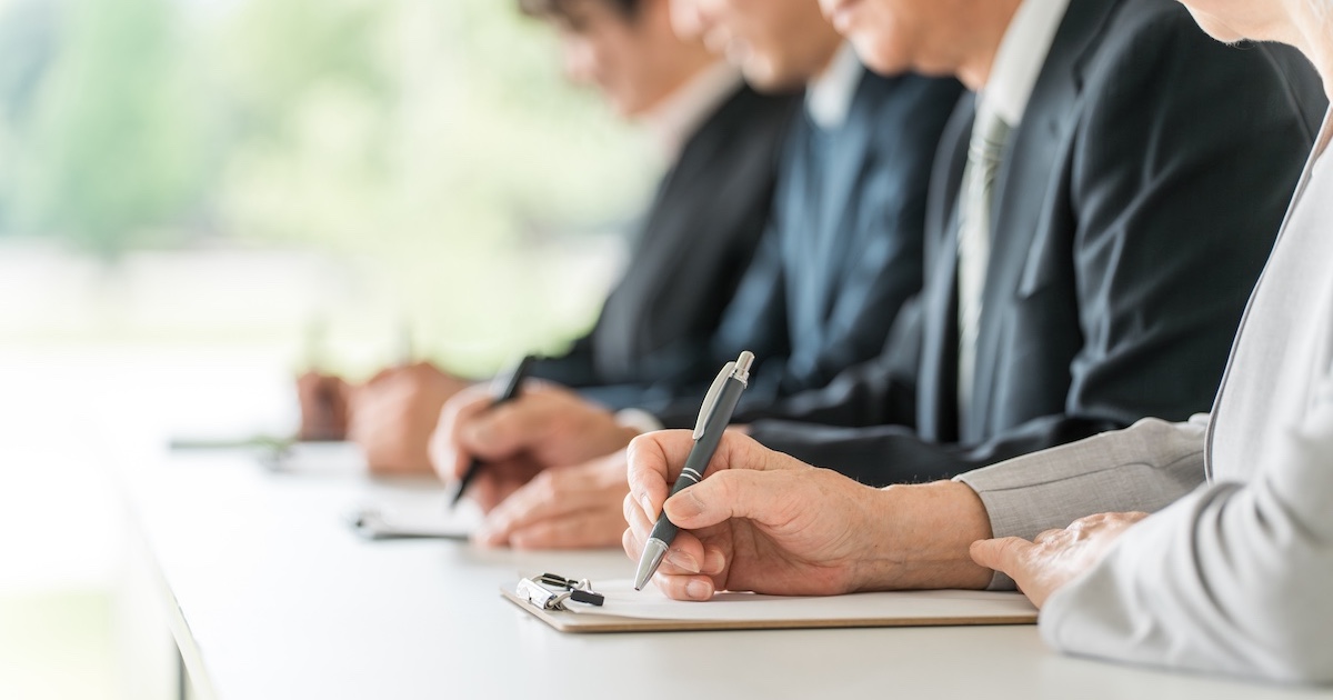 複数のビジネスパーソンがメモをとる手元