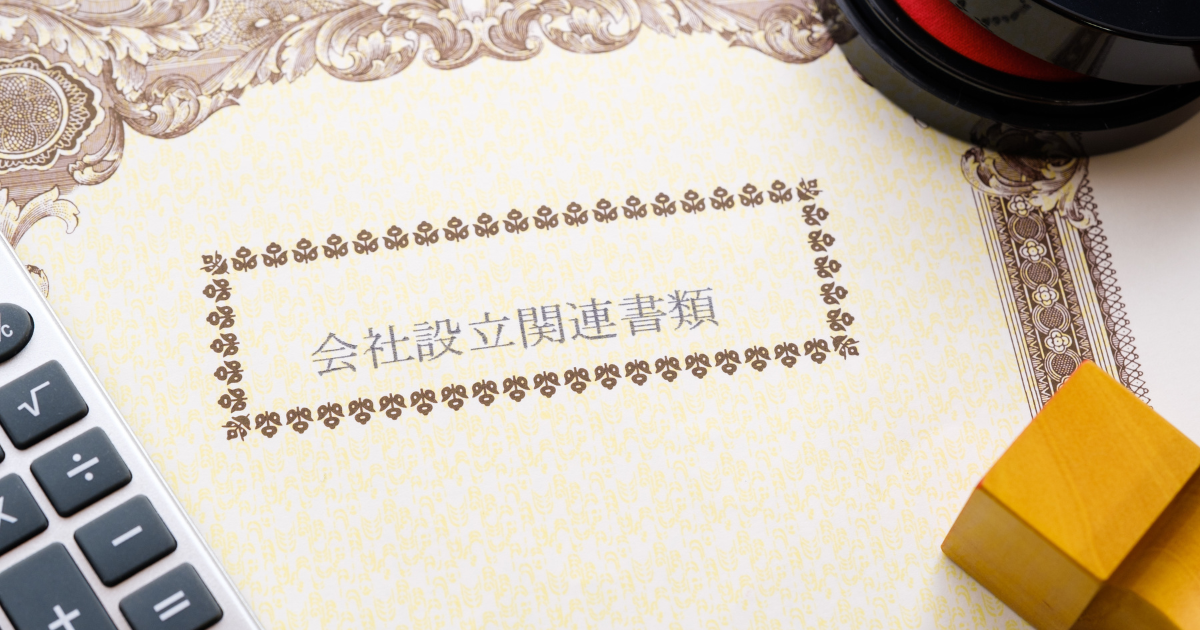 「会社設立登記書類」と書かれた書類と、印鑑・電卓が机の上に置かれている様子