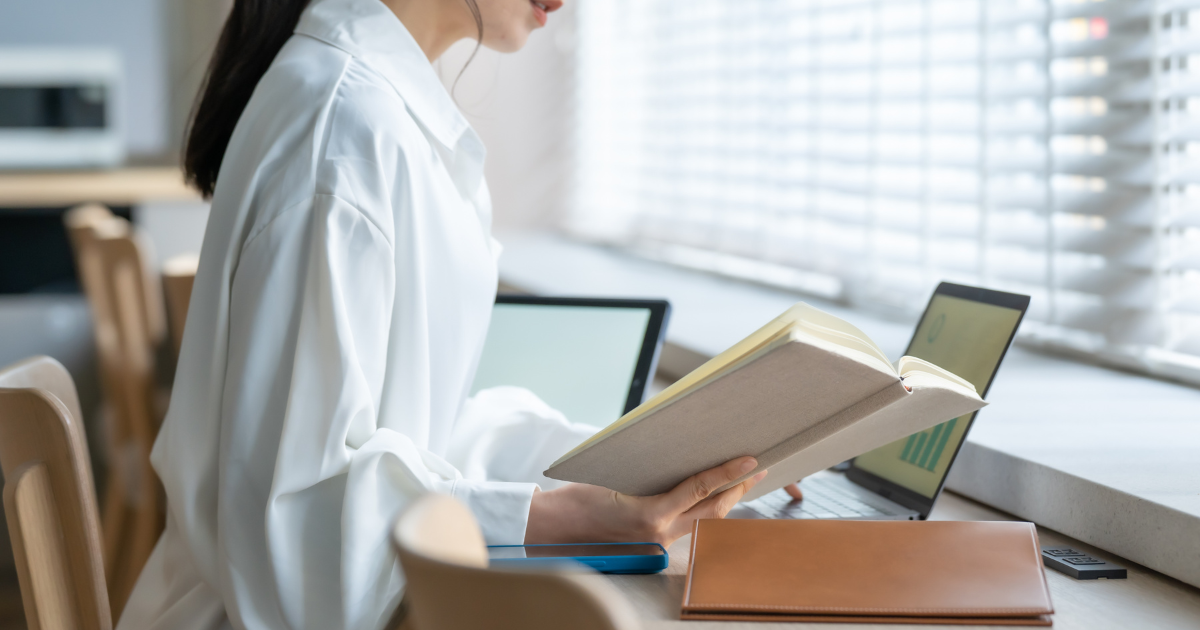 デスクで本を開いて読んでいる女性の様子