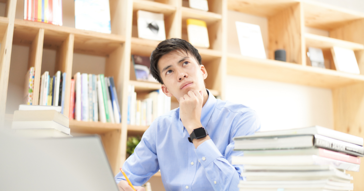 本棚の前で、椅子に座って考え込む男性