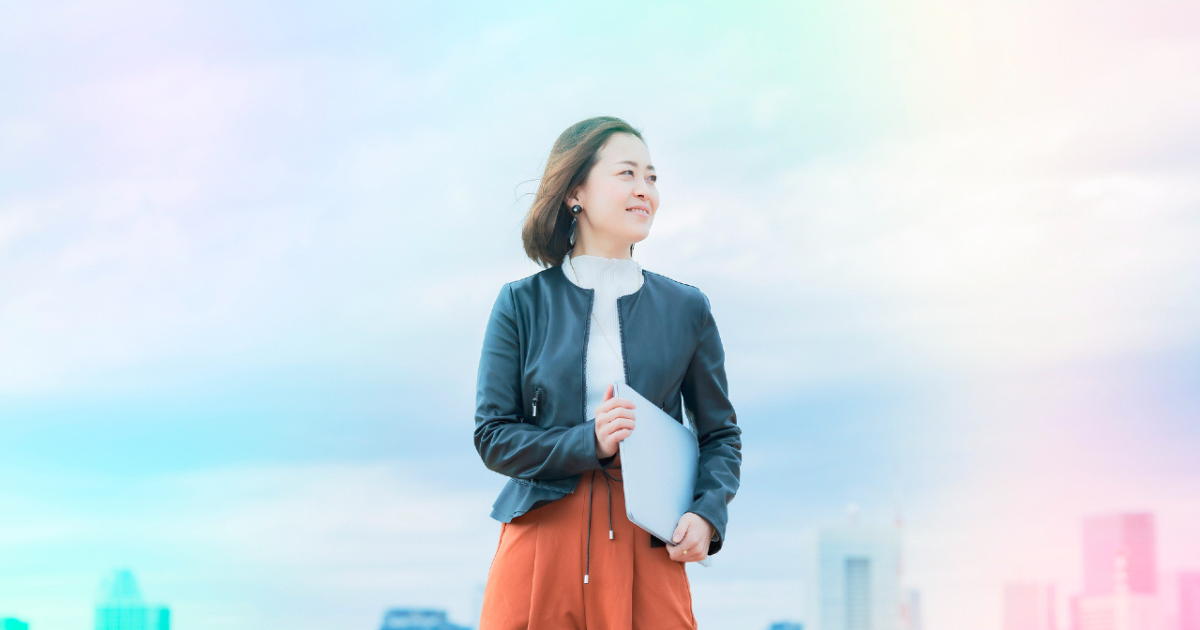 空を背景に、遠くを見ながら立つ女性