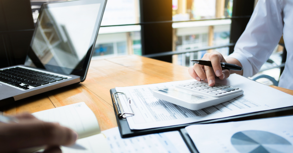 オフィスの机で、書類とノートパソコンを前に打ち合わせを行うビジネスシーン