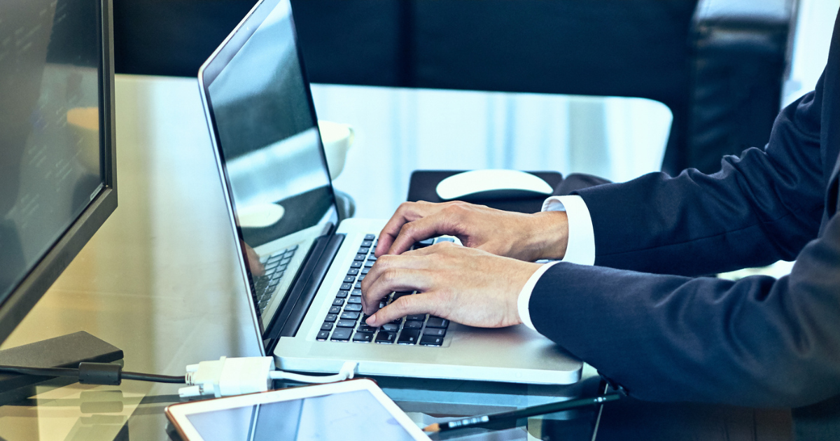 デスクに座り、ノートパソコンで業務作業を行うビジネスパーソンの手元