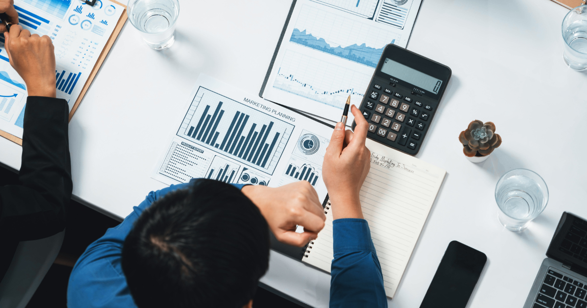 グラフや資料を確認しながら、電卓とタブレットを使って分析を行う様子