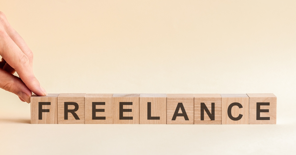 「FREELANCE」と書かれた木製ブロックを指で並べている手元