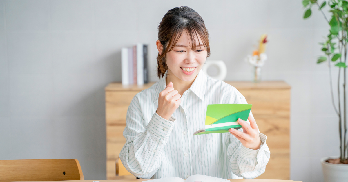 通帳の中身を見て、嬉しそうにガッツポーズをする女性