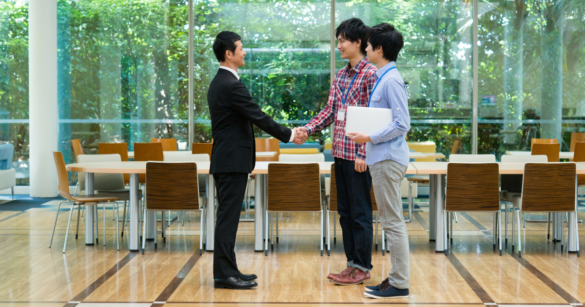 開放的なロビーで握手を交わすビジネスマン