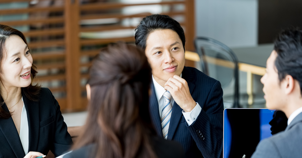 デスクを囲んで熱心に打ち合わせをするビジネスパーソン
