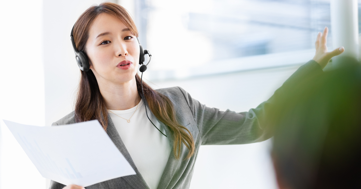 書類を持った女性が前方を指しながら説明している写真