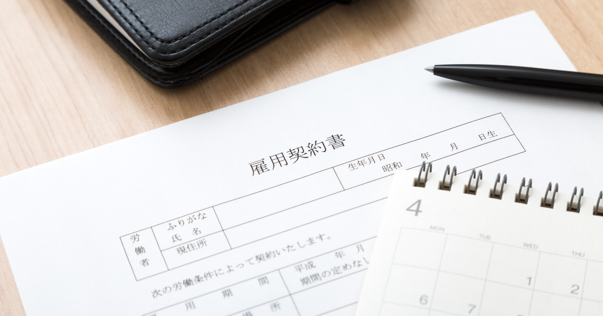 雇用契約書の上にペンやメモ帳が置いてある様子