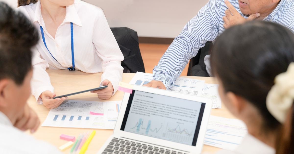 ノートパソコンを囲んで資料を見ながら打ち合わせをする様子