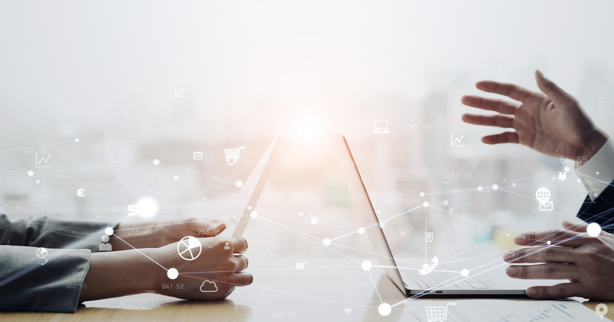 パソコンが置かれた机越しに対話をする2人のビジネスパーソン