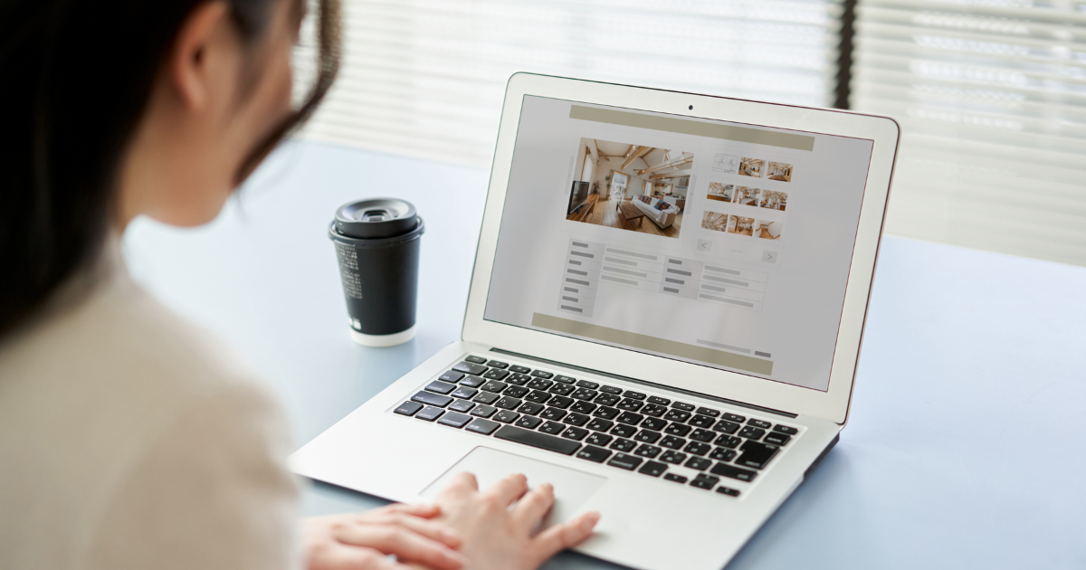 ノートパソコンでウェブサイトを閲覧している背後からの様子