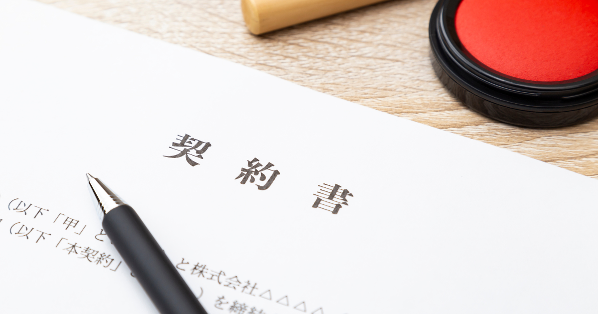 「契約書」と書かれた書類の上にペンが置いてあり、周りに朱肉と印鑑がある