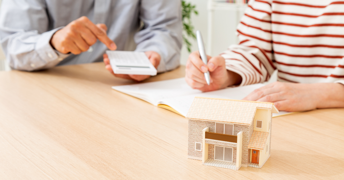 家の模型を前に、電卓を使いながら相談している二人の人物