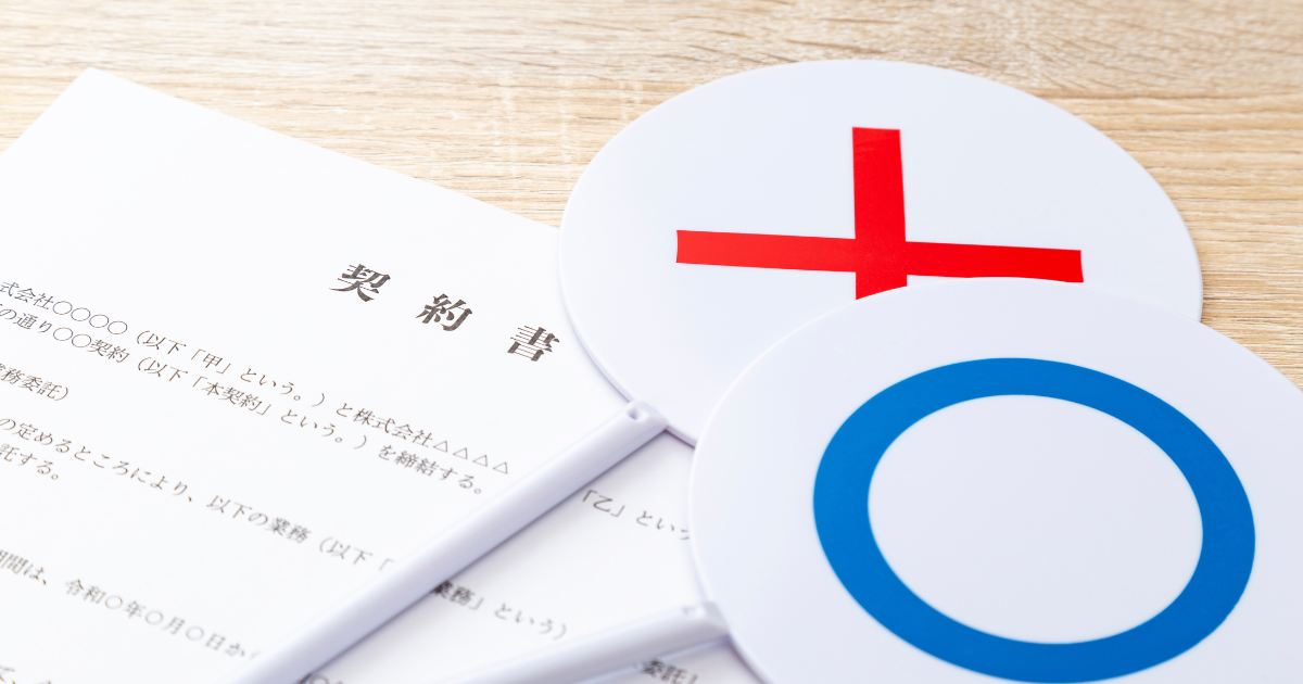 「契約書」と書かれた書類の上に丸とバツのプレートが置いてある