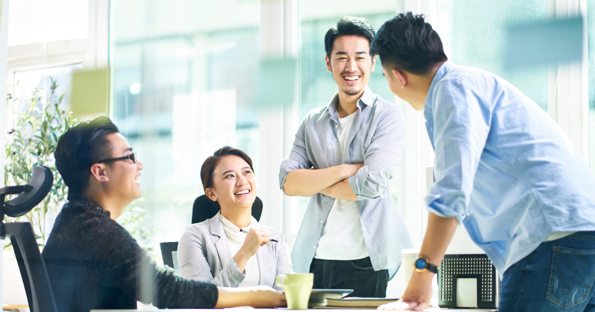 オフィスで立ったまま会話しているビジネスパーソンたちの写真