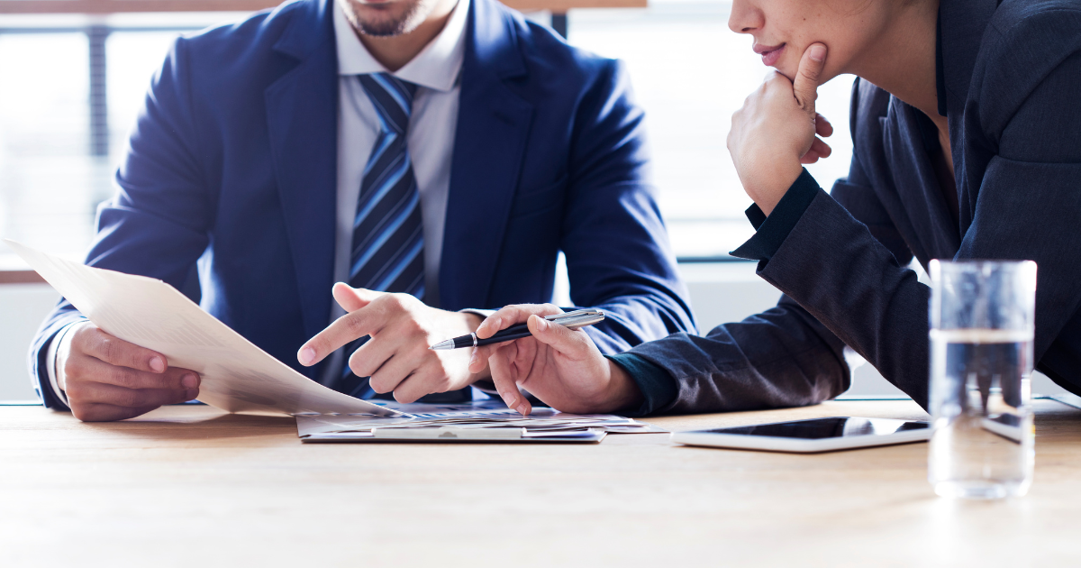 デスクで資料を見ながら打ち合わせをするビジネスパーソン