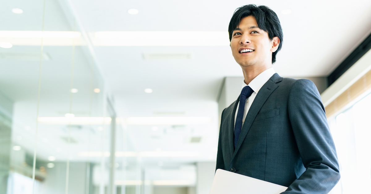 明るい屋内で笑顔を見せるスーツ姿の男性