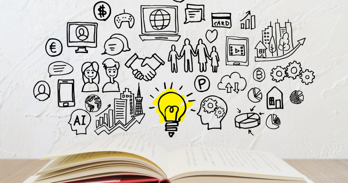 開かれた本から浮かび上がるビジネス関連のイラストと黄色い電球