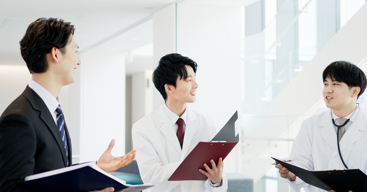 立ち話をするスーツ姿の男性と白衣を着た2人の男性