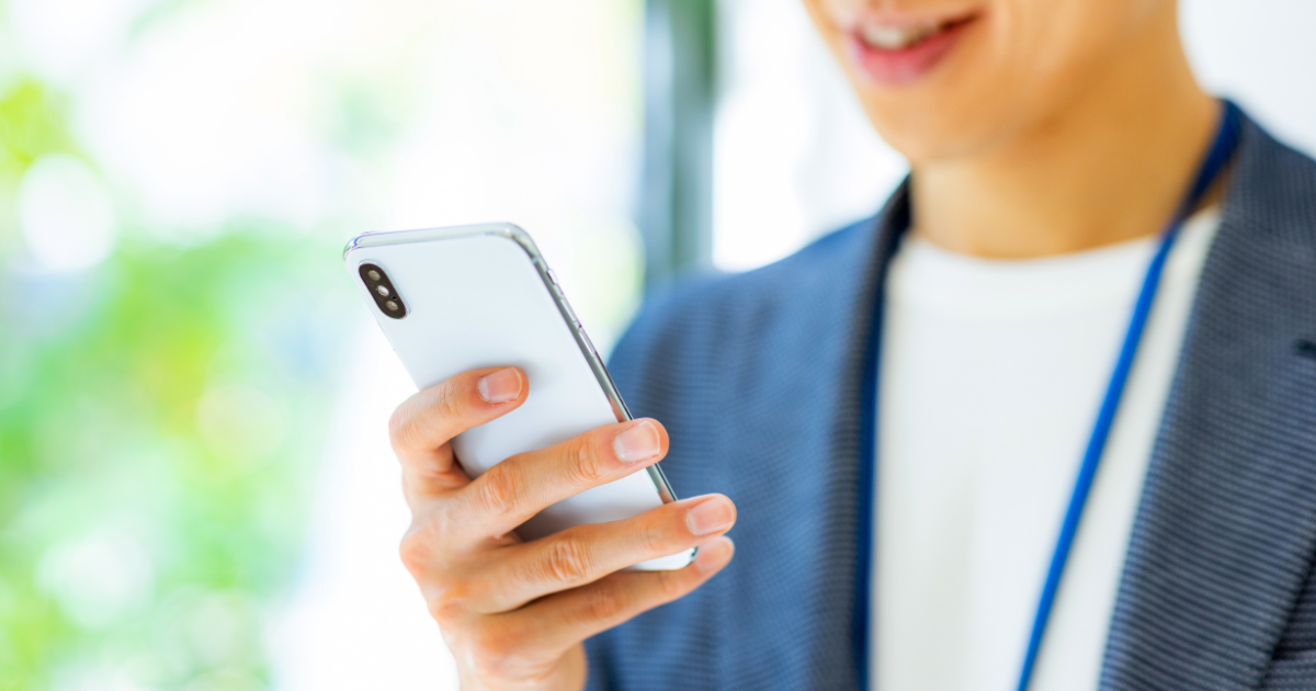 スマートフォンを操作する笑顔のビジネスパーソンの手元