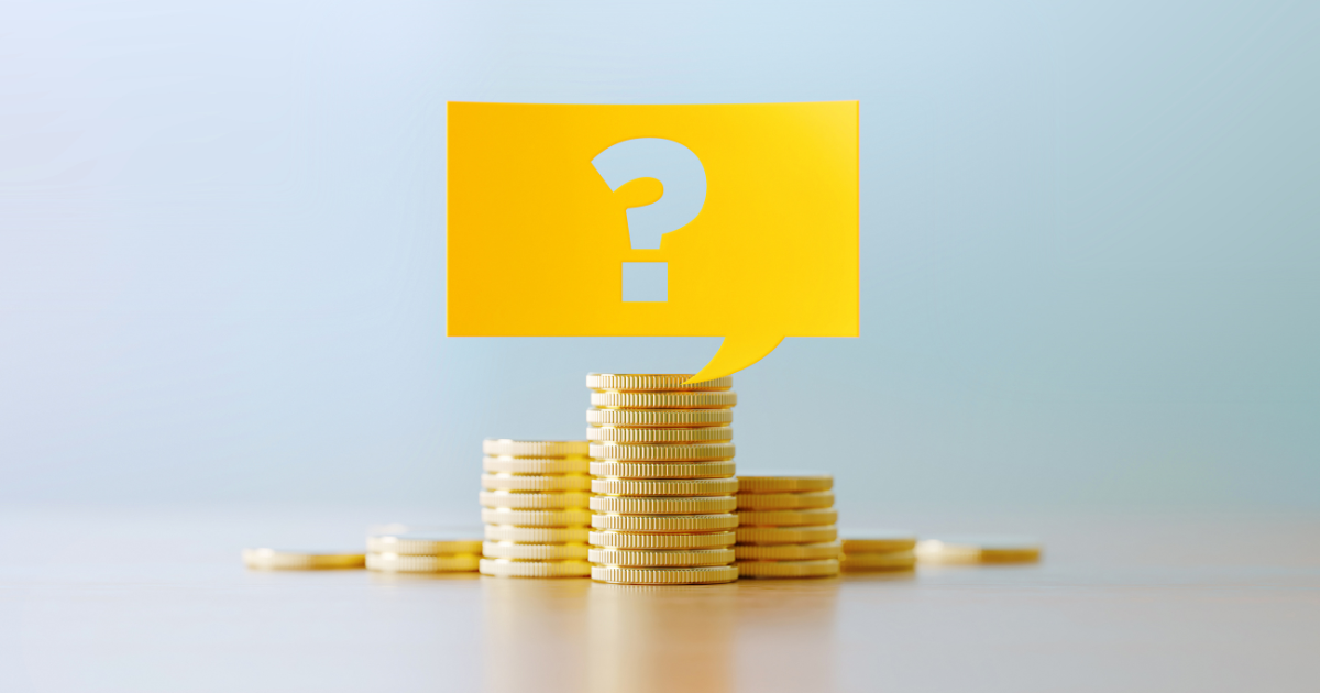 積み上げられた硬貨の上に浮かぶクエスチョンマークの吹き出し