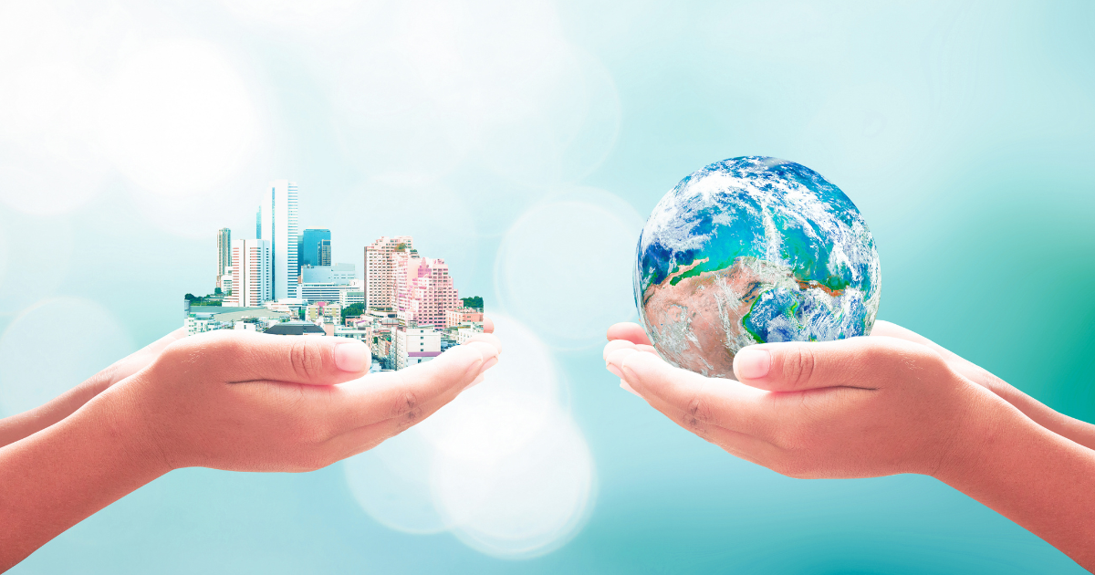 手のひらに乗せられた地球と都市のミニチュア模型