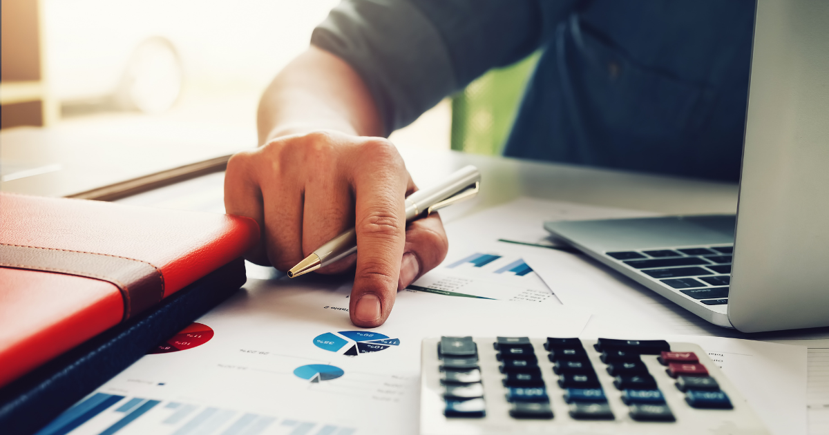 デスク上のグラフ資料をペンで指し示している手元