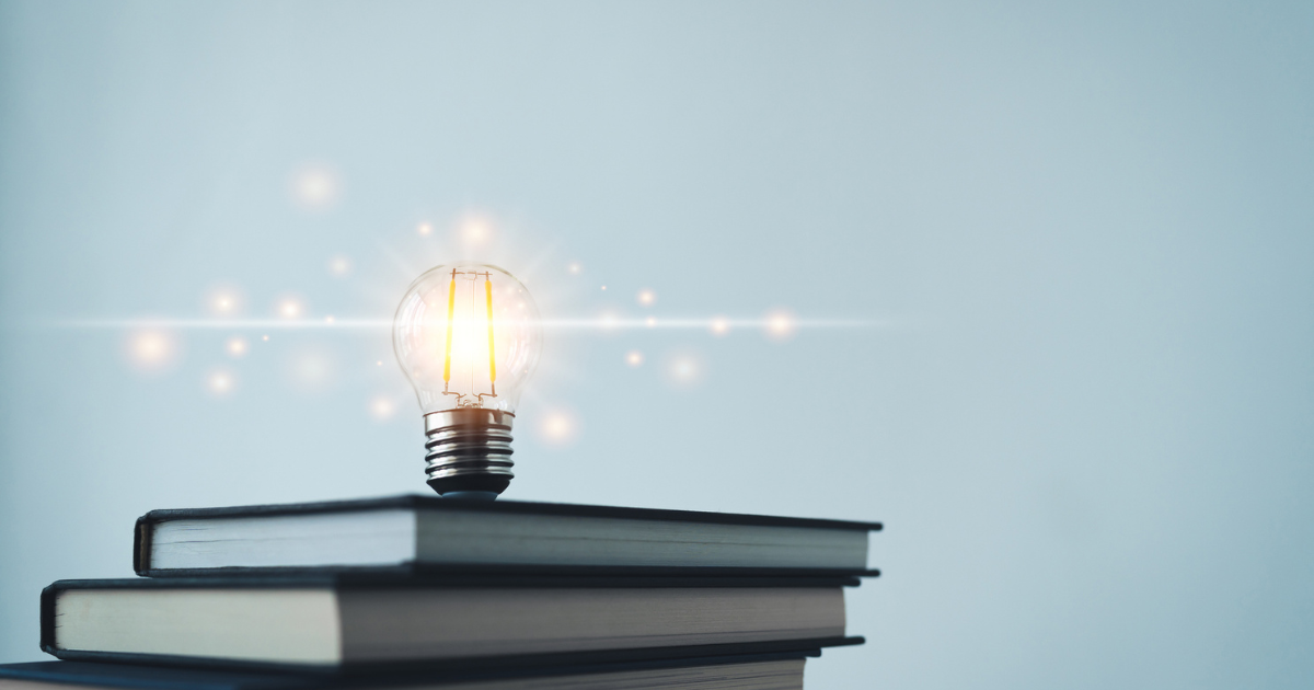 積み重ねられた本の上で光る電球