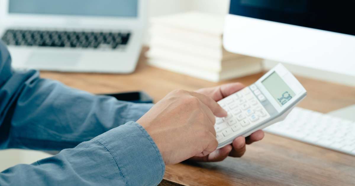 デスク上で白い電卓を操作する手元のアップ
