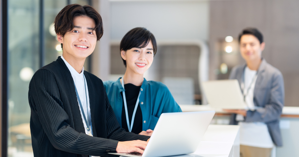 パソコンを前にして笑顔を見せる3人のビジネスパーソン